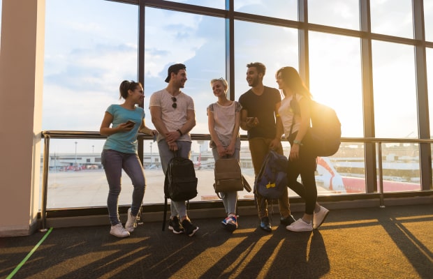 young people group in airport lounge near windows